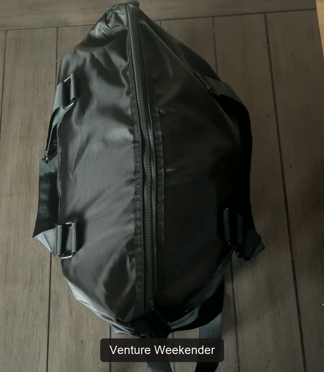 Real packing demonstration of the Venture weekender bag: clothing and overnight essentials, front zip pocket, laptop placement, then zipping and lifting the duffel bag.